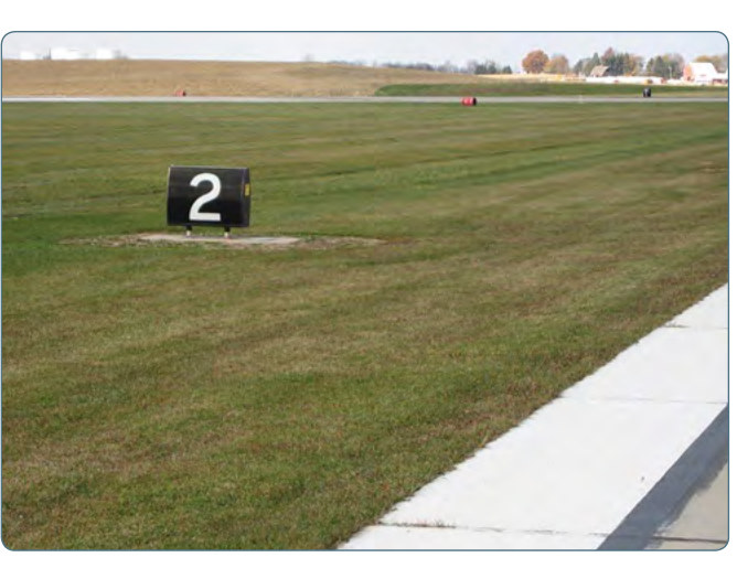 A black sign with a white numeral 2 beside a runway.
